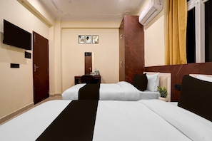 Une chambre d’hôtel avec deux lits, un bureau avec une chaise, un téléviseur à écran plat, un miroir et un appareil de climatisation.