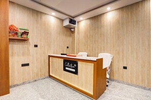A reception desk with a sign, a wooden wall with vertical slats, and a ceiling-mounted air conditioning unit. - Classic With Balcony Chandrashila Residency (Patna)