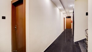En hall med en dörr i trä märkt med siffran ’203’, ett svart klinkergolv och ett handräcke på höger sida.