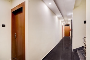 A hallway with a wooden door marked '203', a black tiled floor, and a handrail on the right.