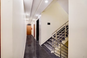 Un couloir avec un escalier, une porte et un luminaire.