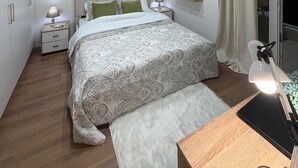 Une chambre moderne avec un lit, des tables de chevet, un miroir et une vue sur l’extérieur.