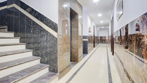 Un vestíbulo de hotel moderno con suelo de mármol, una escalera y un largo pasillo.