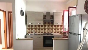 A compact kitchen with a stove, oven, and refrigerator. - Seaside villa with patio, just 250 m / 3 minute walk to the beach (Sicilia)