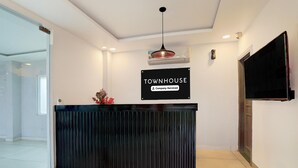 A reception desk with a sign reading 'TOWNHOUSE Company-Serviced,' a flat-screen TV, and a modern ceiling design. - Deluxe BSA Townhouse (Lucknow)
