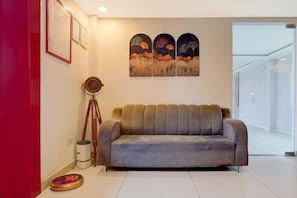 Un salon moderne avec un canapé gris, un trépied et des certificats encadrés accrochés au mur.