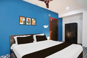 A bedroom with a bed, a ceiling fan, a wardrobe, and wall art. - Classic With Balcony Noonmati Guwahati Sundari (Guwahati)
