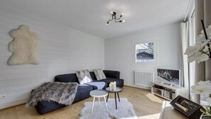 Una sala de estar moderna con un sofá, dos mesas auxiliares, una chimenea, un televisor y una ventana con vistas.