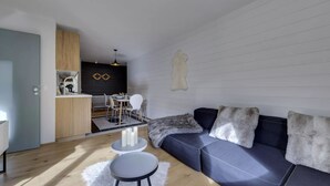 Una sala de estar moderna con sofá, mesa de comedor y zona de cocina.