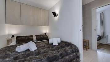 A bedroom with a large bed, a wardrobe, a nightstand, and a wall-mounted light fixture.