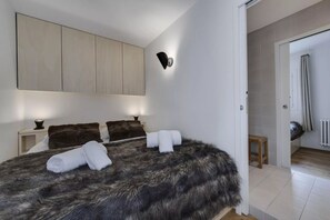A bedroom with a large bed, a wardrobe, a nightstand, and a wall-mounted light fixture. - Oréades 101, sunny Renovated Apartment with Balcony, Central Val d’Isère (Val-d'Isère)