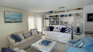 Ein Wohnzimmer mit einer Couch, einem Couchtisch, einem Bücherregal und einem Bild an der Wand.
