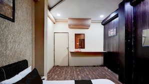A hotel room with a bed, a desk, a mirror, and a wardrobe. - Super Lokmanya Formerly Siddhivinayak (Nagpur)