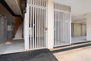 A building entrance with metal gates, a staircase, and a concrete floor.
