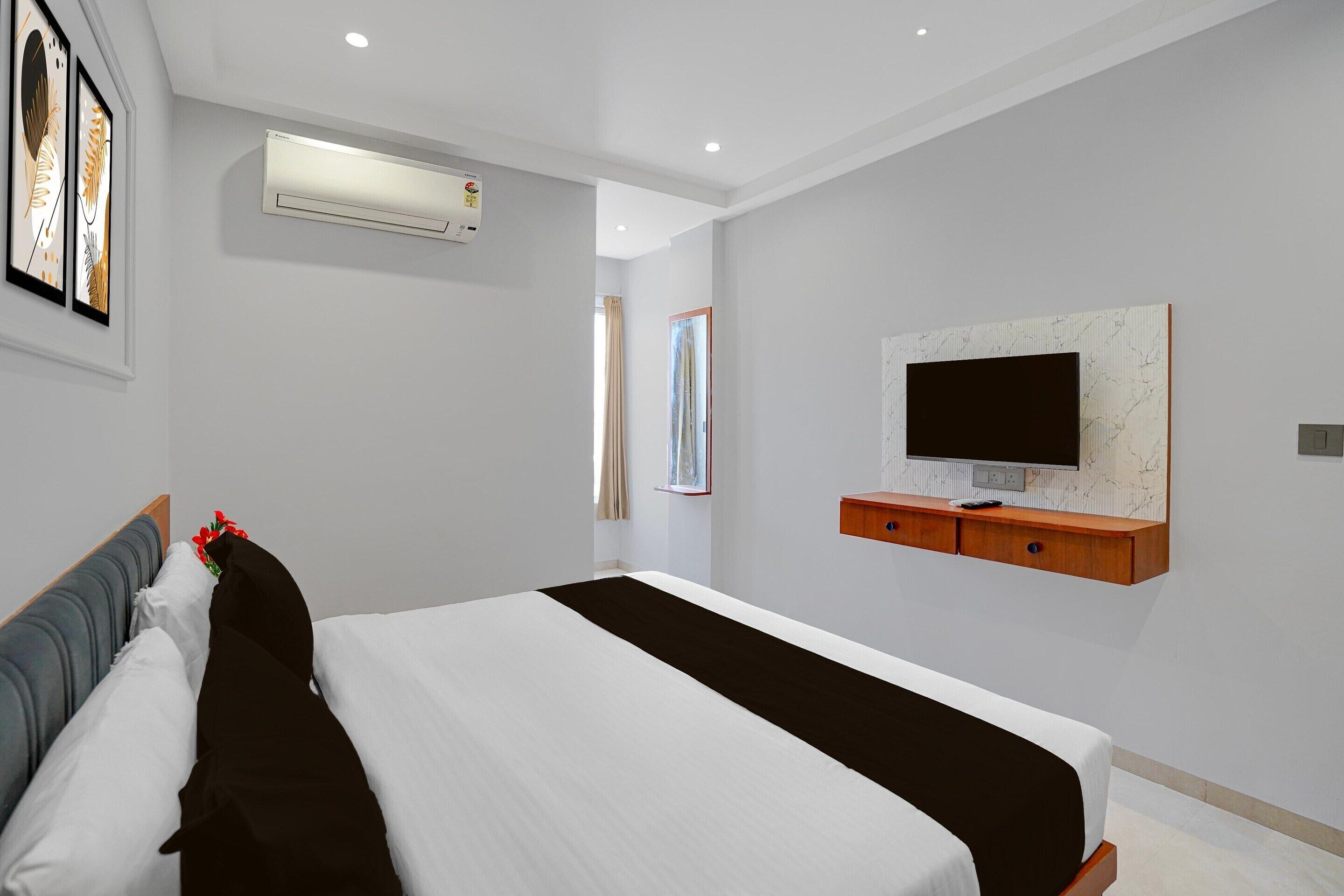 Ein modernes Hotelzimmer mit einem großen Bett, einem Wand-Fernseher und einer Klimaanlage.