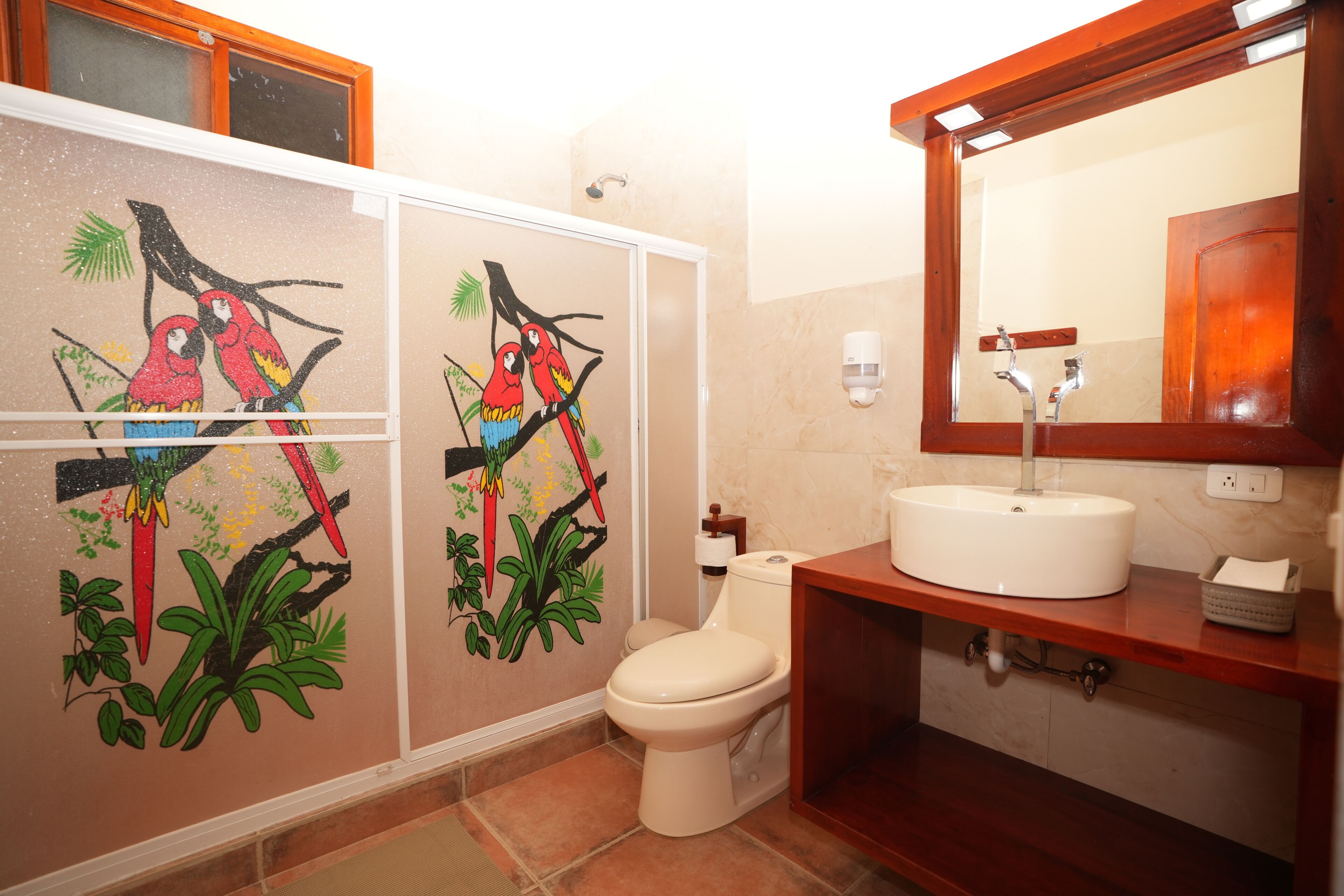 Casa de banho com sanita, lavatório, espelho e decoração na parede.