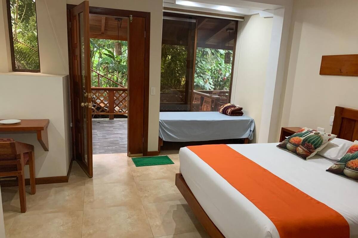 A bedroom with a bed, a desk, and a view of the outdoors.