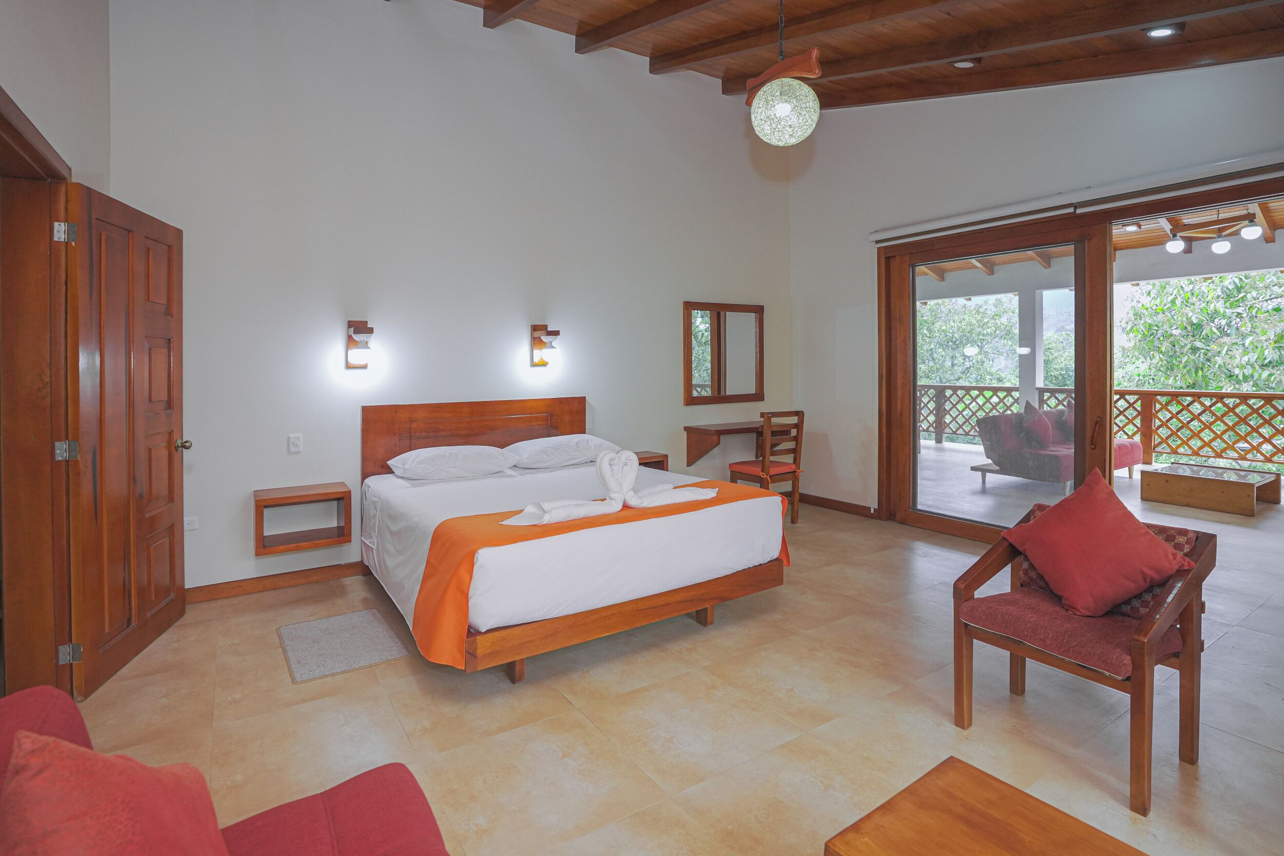 A bedroom with a bed, a chair, a nightstand, and a large window.