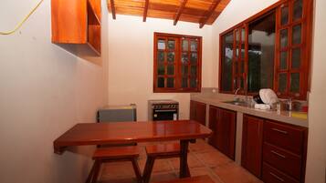 A kitchen with wooden cabinets, a tiled floor, a wooden table, and a window with a view.
