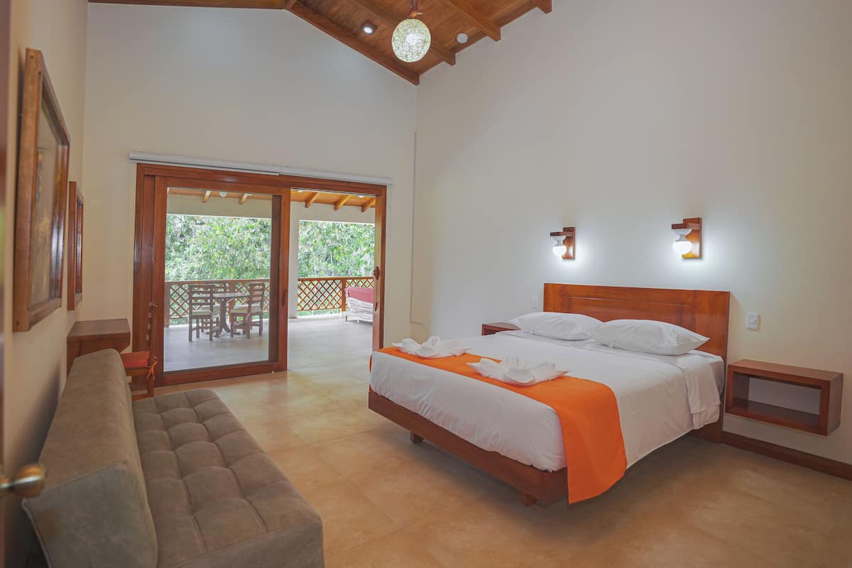A bedroom with a bed, a bench, a wooden headboard, and a sliding glass door leading to an outdoor area.