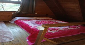 A wooden room with a bed, a window, and a wooden ceiling.