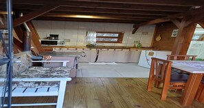 A cozy attic-style room with a sofa, dining table, and kitchen area.