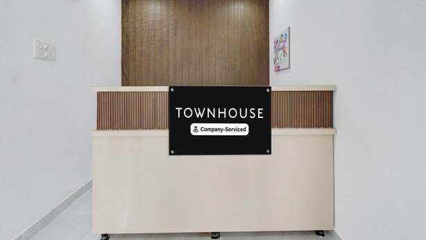 Een receptiebalie met een bord waarop 'TOWNHOUSE Company Serviced' staat.