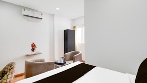 Een hotelkamer met een bed, een stoel, een bureau, een airconditioner en een raam.