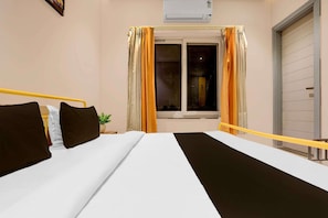 Una habitación de hotel con una cama, cortinas, un equipo de aire acondicionado y una ventana.