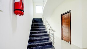 Una escalera con un extintor en la pared, una puerta de madera y una ventana en la parte superior.
