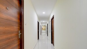 Un pasillo con puertas de madera, paredes blancas y un suelo brillante.