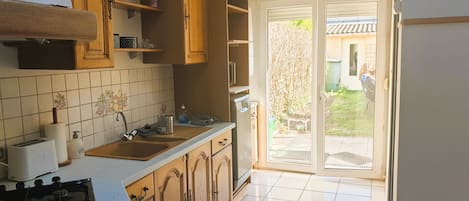 Uma cozinha com armários de madeira, fogão a gás, pia e uma porta de vidro deslizante para um pátio.
