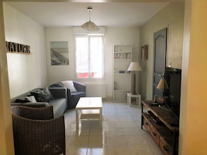A living room with a sofa, a coffee table, a lamp, a television, and a bookshelf.