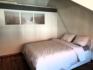 A bedroom with a bed, a nightstand, and three wall-mounted pictures depicting a beach scene.