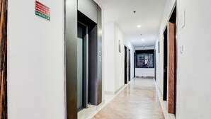 A long, narrow hallway with doors on both sides, a tiled floor, and a sign indicating a stair case is used in case of fire. - Super Deluxe Room Golden Temple Amritsar A Star (Amritsar)