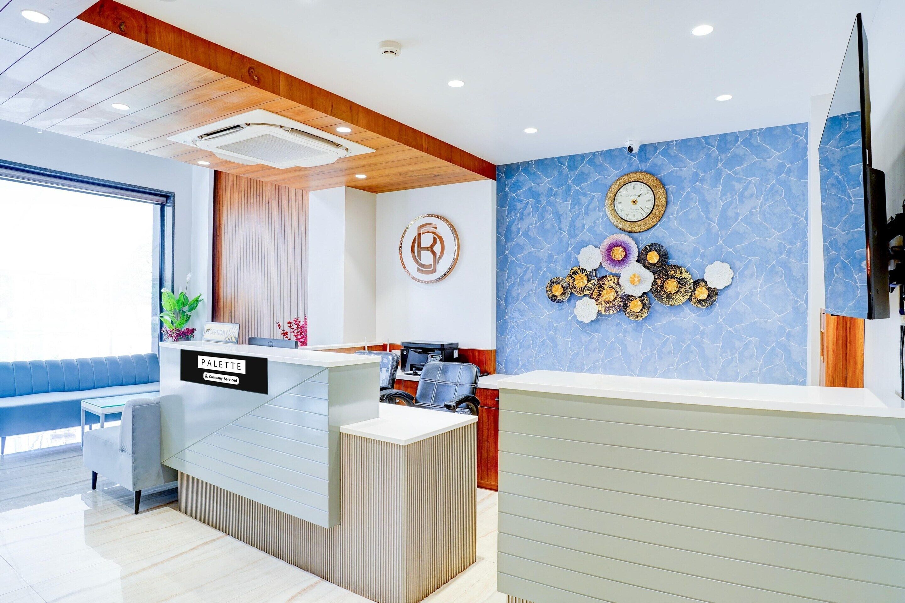 A reception area with a modern design, including a blue marble wall, a clock, and a logo on the wall.