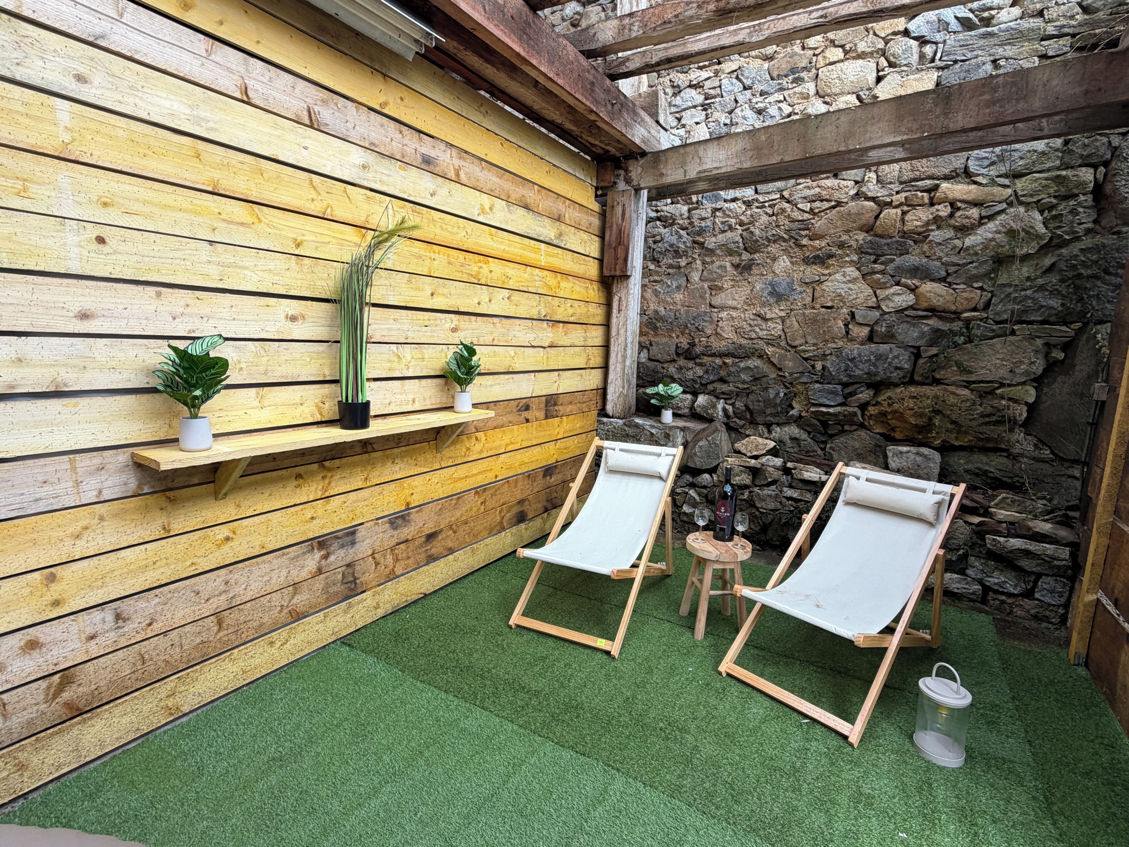 A wooden wall with shelves, two lounge chairs, and a stone wall.