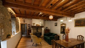 A rustic interior with a stone wall, wooden beams, a fireplace, a sofa, a dining table, and chairs. - La Petite Maison - Spa - Games room - Air conditioning - Garden (Arguenos)