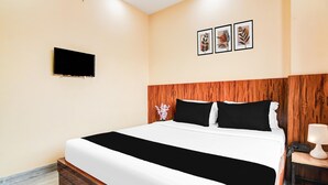 A hotel room with a bed, a TV mounted on the wall, and a nightstand with a lamp. - Netaji Subhash Chandra Bose Airport (Barakpur)