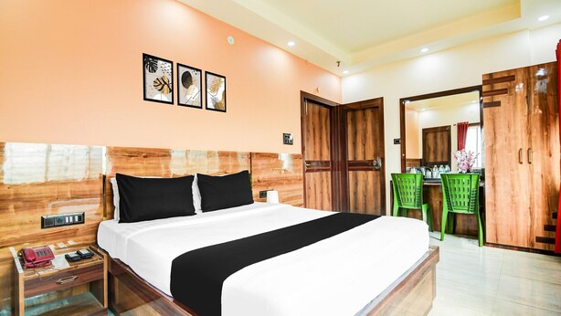 A hotel room with a large bed, wooden headboard, a desk with chairs, and a bathroom visible through an open door. - Netaji Subhash Chandra Bose Airport (Barakpur)