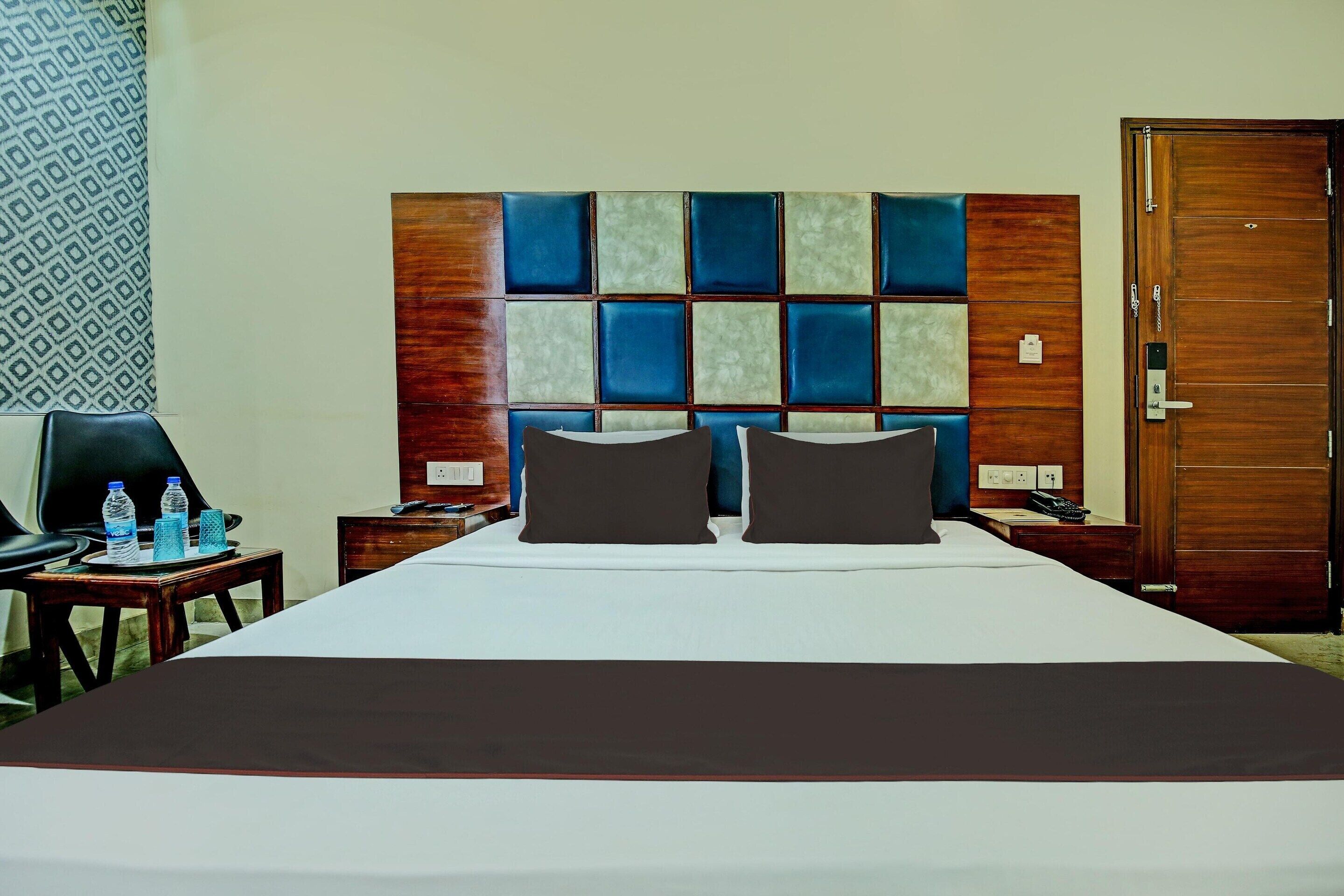Een hotelkamer met een groot bed, een houten hoofdeinde, een bureau met een stoel en een deur.