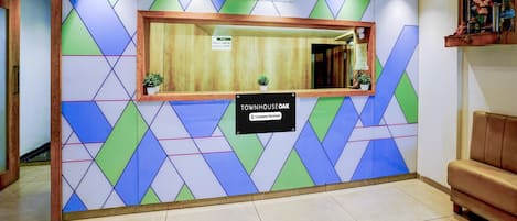 A reception area with a geometric patterned wall, a reception desk, and a sign indicating 'Company Serviced'.