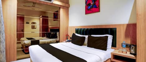 Una camera d'albergo con un letto grande, un armadio, uno specchio, un quadro appeso al muro e un condizionatore d'aria.