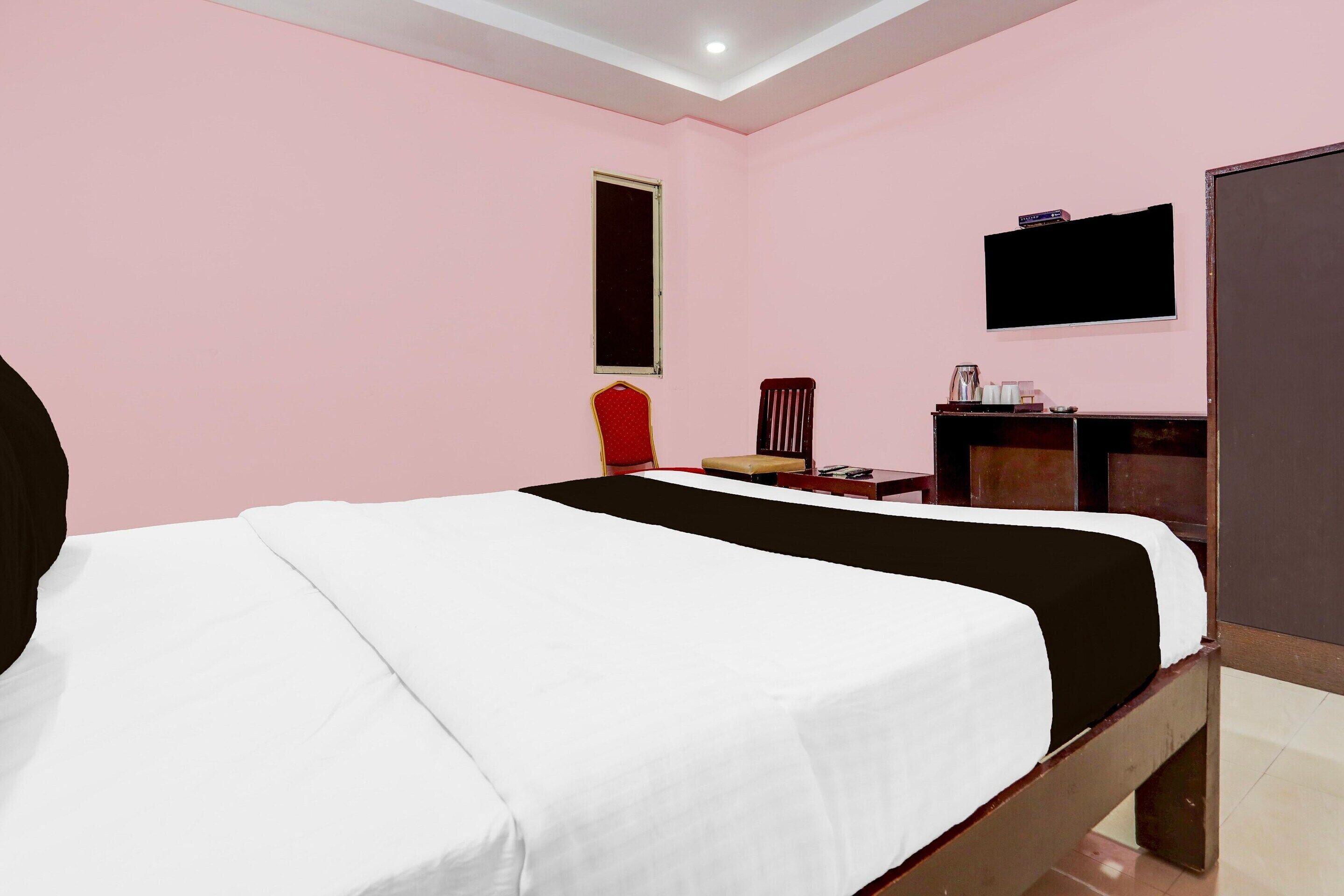 A bedroom with a bed, a television, a wardrobe, and a window.