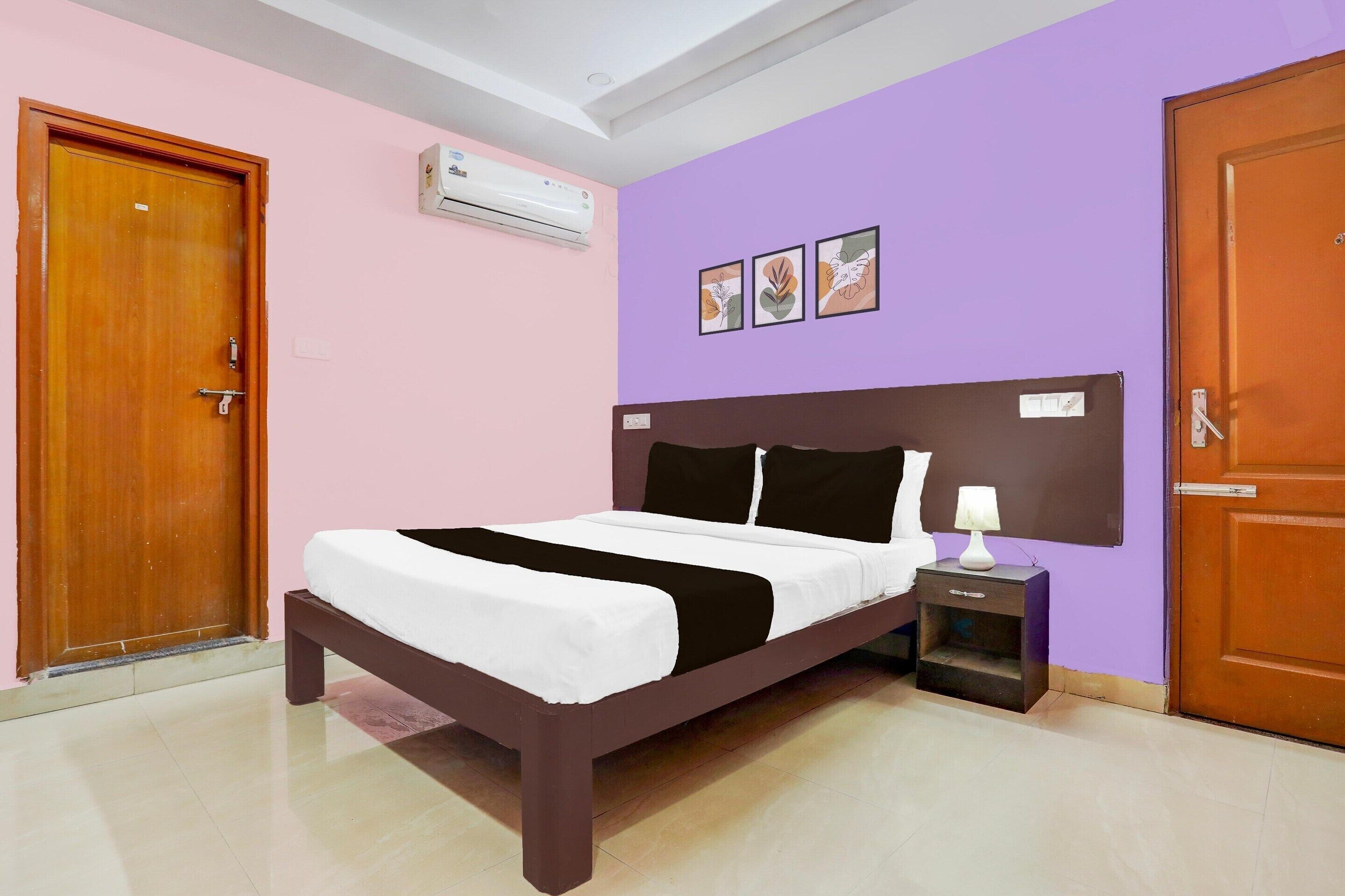 Un dormitorio con una cama, una mesita de noche, aire acondicionado de pared y una puerta.