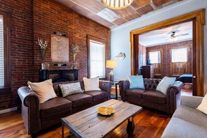 Ein Wohnzimmer mit Backsteinwänden, Ledersofas, einem Holztisch und einem Kamin.