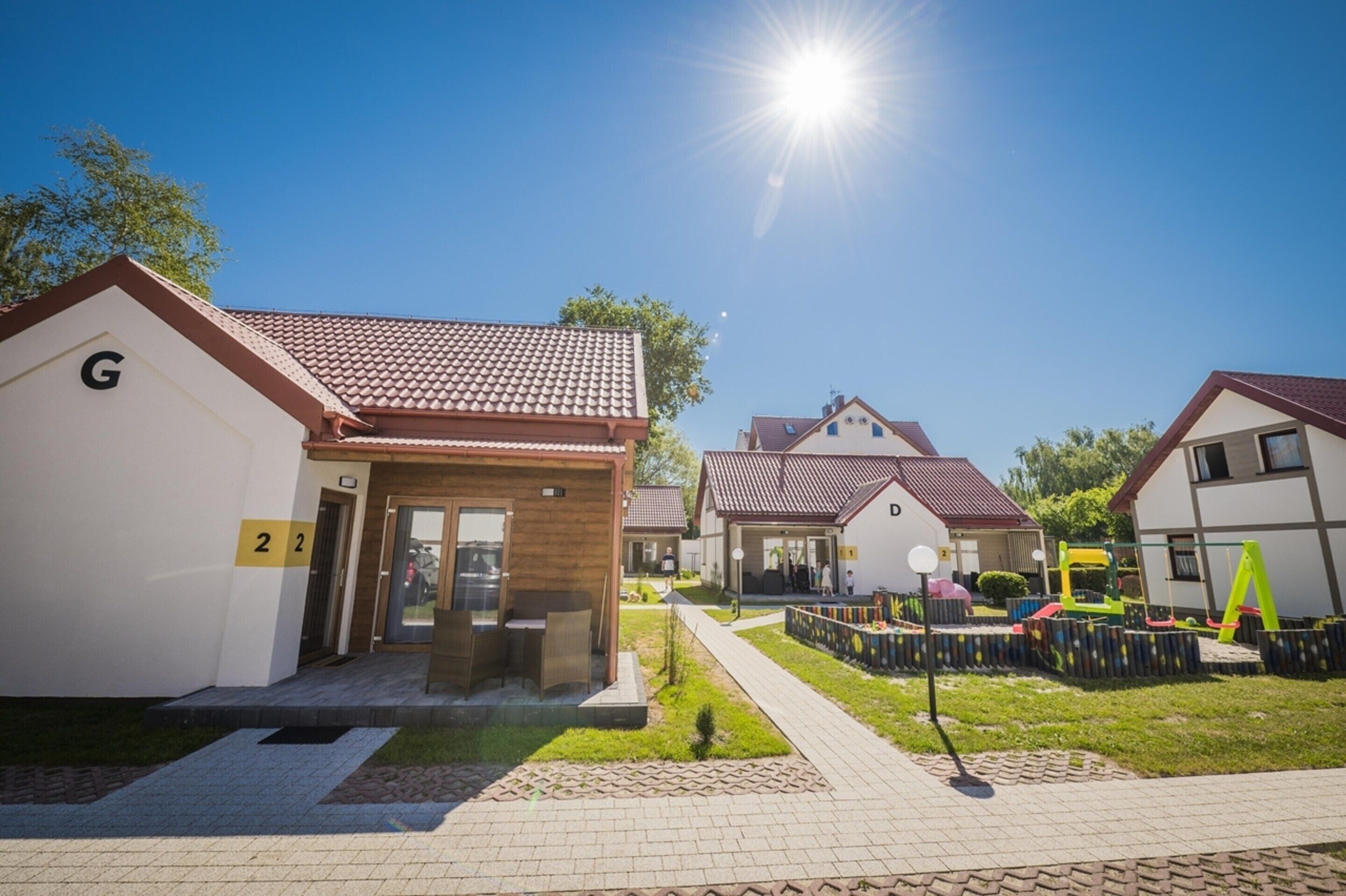 Zona residencial con casas numeradas, un sendero pavimentado y un parque infantil.