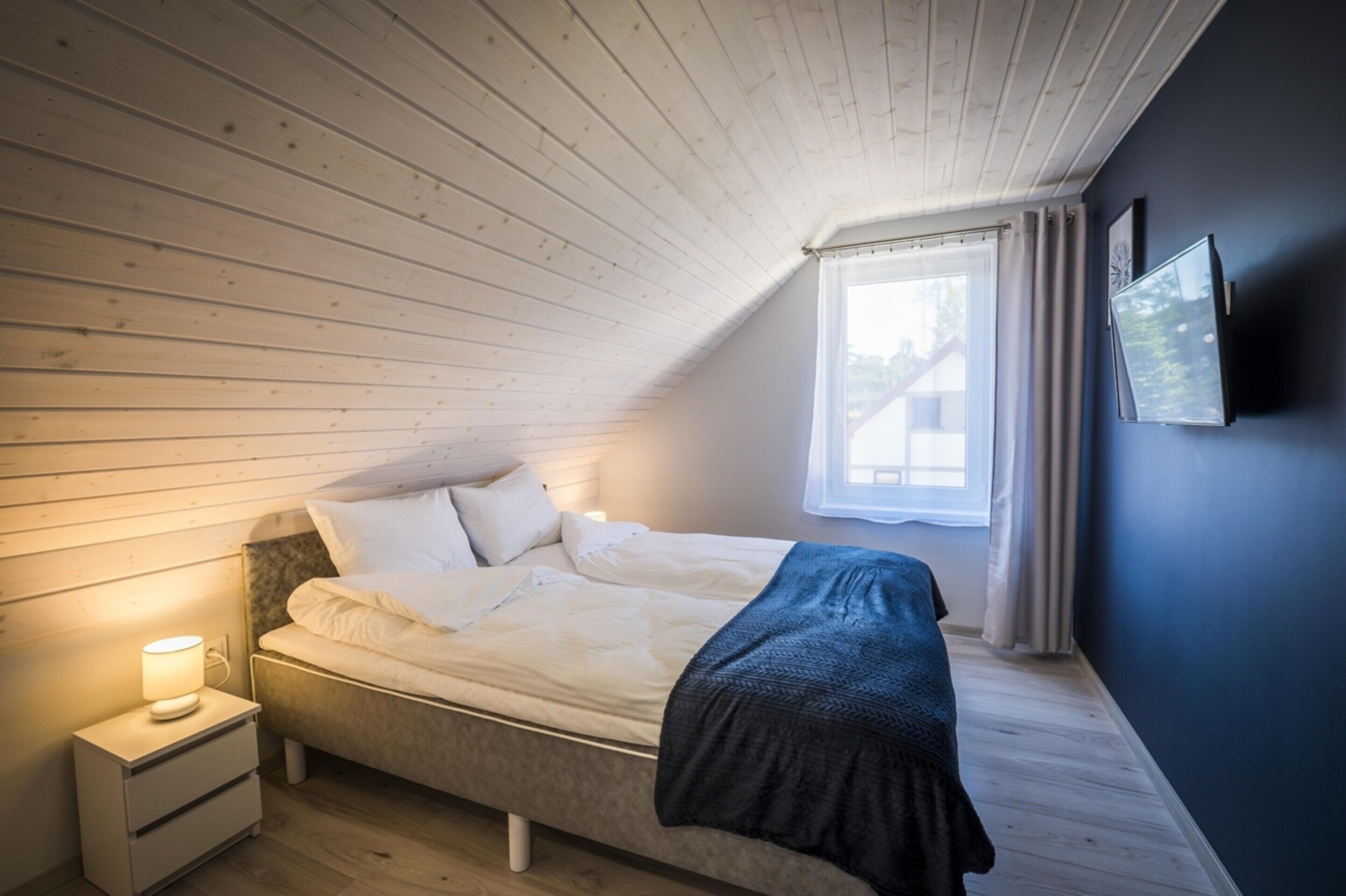 Un dormitorio con cama, mesita de noche y ventana.