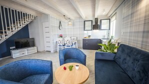 A modern living room with a sofa, chairs, a coffee table, a TV, and a staircase. - Two-story Holiday Home for 5 People, Summer Pool (Leba)