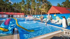 A swimming pool with a slide, lounge chairs, and a building with a red roof. - Two-story Holiday Home for 5 People, Summer Pool (Leba)
